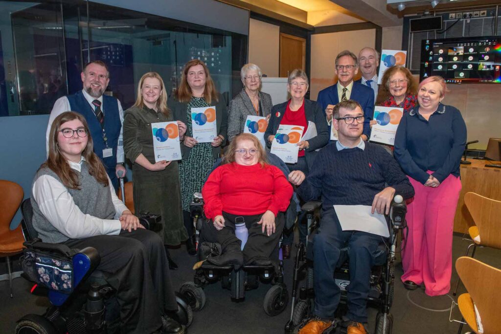Access to Politics Network Members and Senedd Members are in a group holding the Charter, looking delighted that it's out in the world. Present are Access to Politics Project Officer Kat Watkins, Network members Briallen Symons-East, Lee Ellery, Paul Allchurch, Lisa Pritchard & Michael Whittaker, along with Members of the Senedd at the time.