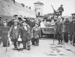 A crowd of wounded war veterans and other disabled people gathered beside an army tank. Tall walls enclose the space and a guard / watch tower is seen in the background