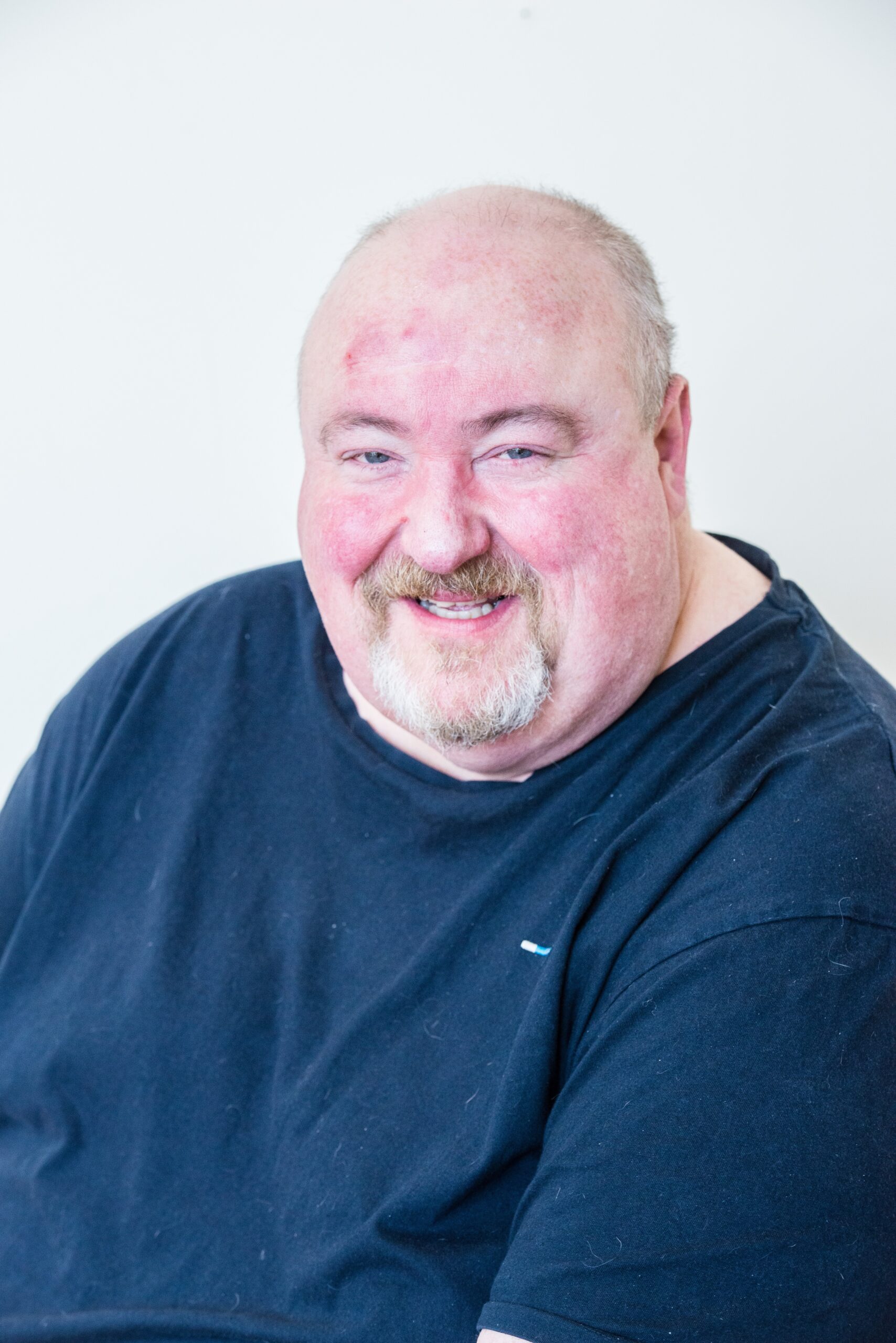 Board member, Kelvin, smiling at the camera. He wears a dark green jumper.