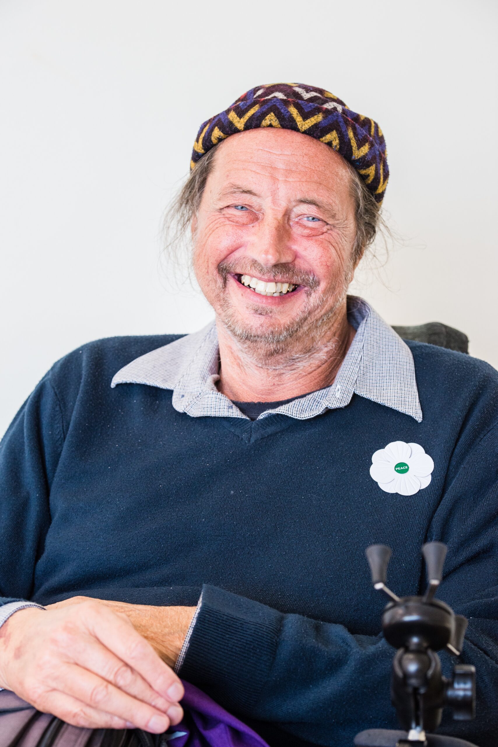 Board member, Trevor, smiling widely at the camera. He wears a black jumper with a grey shirt collar poking out from the top.