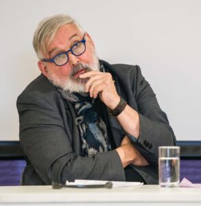 Graham Findlay in a thoughtful pose as a speaker at DW's 50th anniversary conference. His left hand is raised to his mouth and he looks as if he's listening intently to a contribution from the audience.